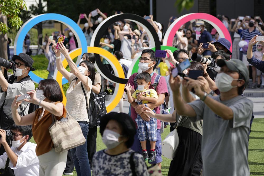 People gather near the National Stadium in Tokyo, Japan, as Blue Impulse of the Japan Air Self-Defence Force practice ahead of the 2020 Summer Paralympics on Aug 22. &mdash; AP