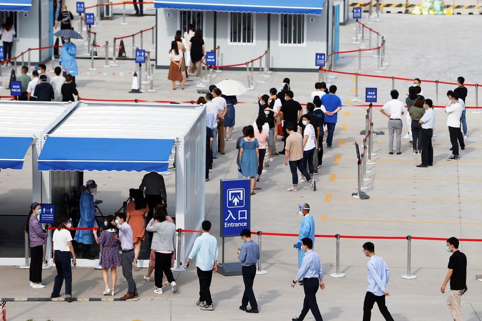 Staff members of Shanghai Pudong International Airport line up at a nucleic acid testing site to test for the coronavirus in Shanghai on August 20. — Reuters