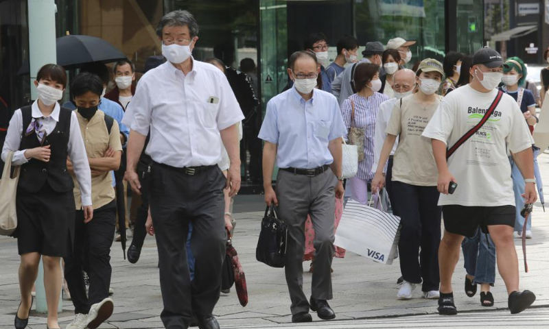 People wearing face masks to help protect against the spread of the coronavirus walk on a street in Tokyo on Monday. — AP