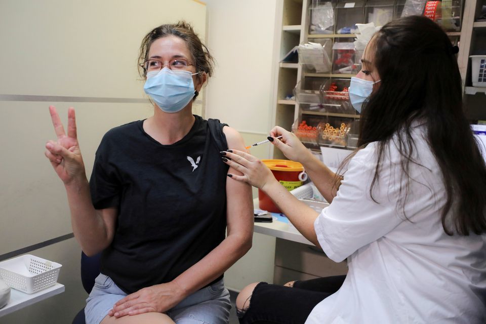 An Israeli woman poses for a picture as she receives a third shot of coronavirus vaccine as Israel launches booster shots for over 40-year-olds, in Jerusalem on August 20. &mdash; Reuters