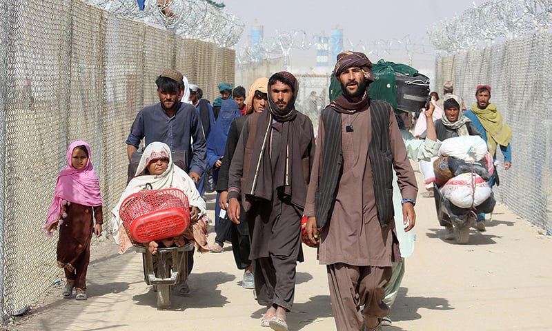 Afghan people walk inside a fenced corridor as they enter Pakistan at the Pakistan-Afghanistan border-crossing point in Chaman on August 25. — AFP