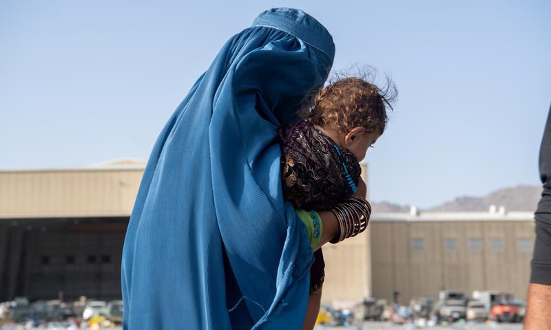 This file photo shows a woman carrying a child as passengers board a US Air Force C-17 Globemaster III assigned to the 816th Expeditionary Airlift Squadron in support of the Afghanistan evacuation at Hamid Karzai International Airport in Kabul, Afghanistan. — Reuters/File