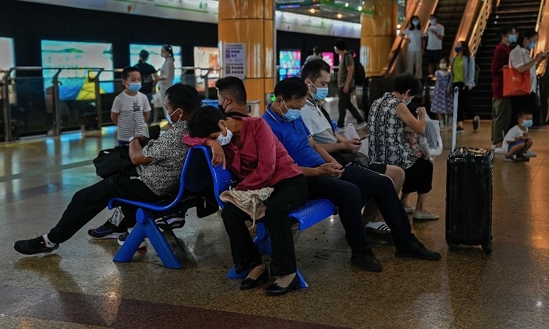 Commuters wearing face masks to help curb the spread of the coronavirus rest on a bench as they wait for their trains inside a subway station in Shanghai on August 29. — AP