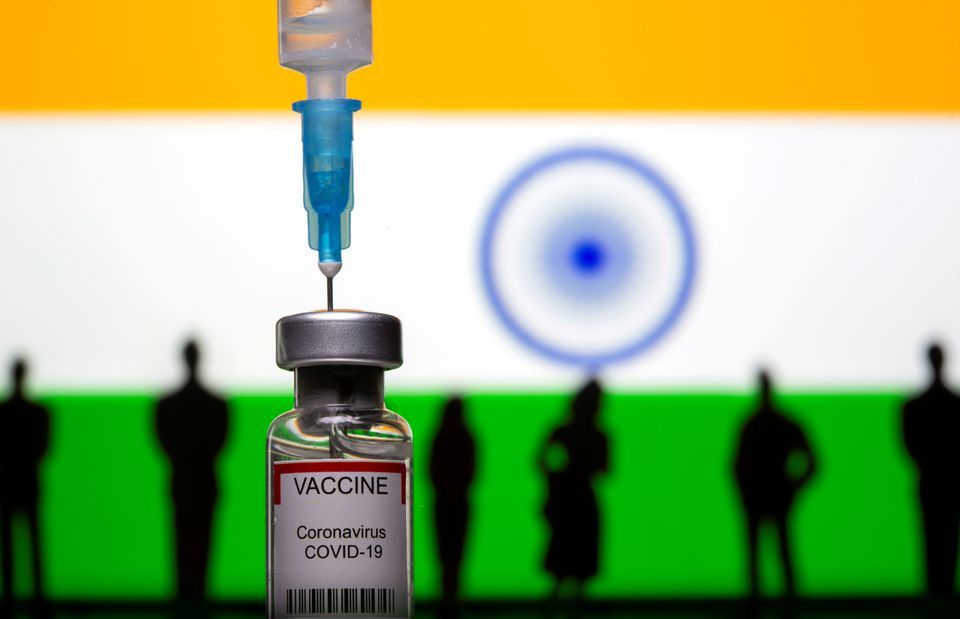 3D-printed toy figurines, a syringe and a vial labelled "coronavirus vaccine" are seen in front of the Indian flag. — Reuters/File