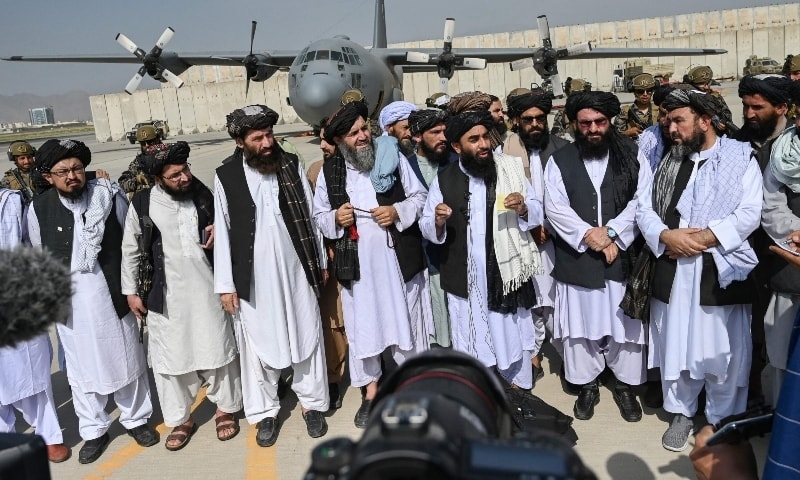 Taliban spokesman Zabihullah Mujahid (C, with shawl) speaks to the media at the airport in Kabul on August 31. — AFP