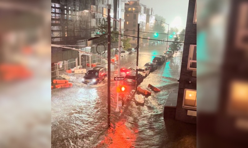 A vehicle moves along a flooded road as safety barriers float in floodwaters in Williamsburg, New York City, in this still image taken from video obtained from social media. &mdash; Reuters