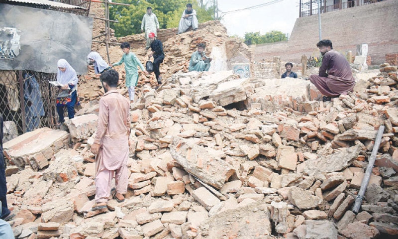 SOME schoolgirls struggle to make their way into their Pucca Qila residences as labourers work to remove debris of its collapsed facade on Thursday.—Dawn SOME schoolgirls struggle to make their way into their Pucca Qila residences as labourers work to remove debris of its collapsed facade on Thursday.—Dawn