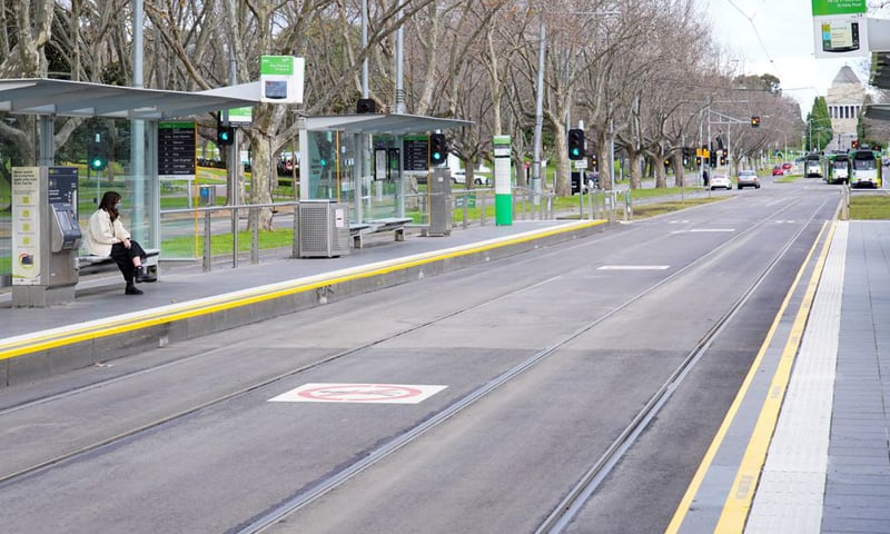 This file photo shows a lone passenger sitting at a tram stop on a mostly-empty city centre street on the first day of a lockdown as the state of Victoria. &mdash; Reuters/File