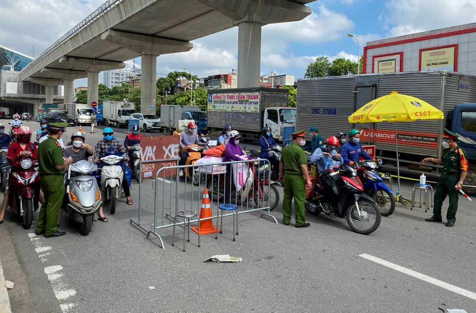 Vietnam police officers inspect authorised travel documents of commuters at a checkpoint during the first day of the extended lockdown in Hanoi, Vietnam on September 6. — Reuters