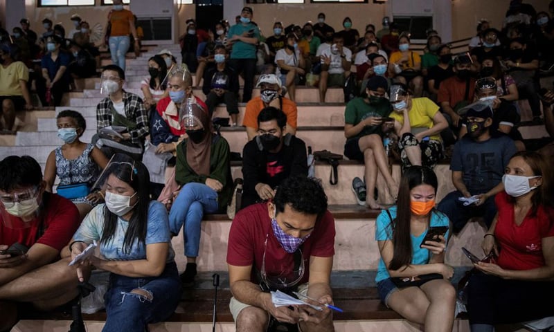 In this file photo, Filipinos use their smartphones while queueing for free vaccination against Covid-19 at San Andres Sports Complex in Manila. — Reuters/File