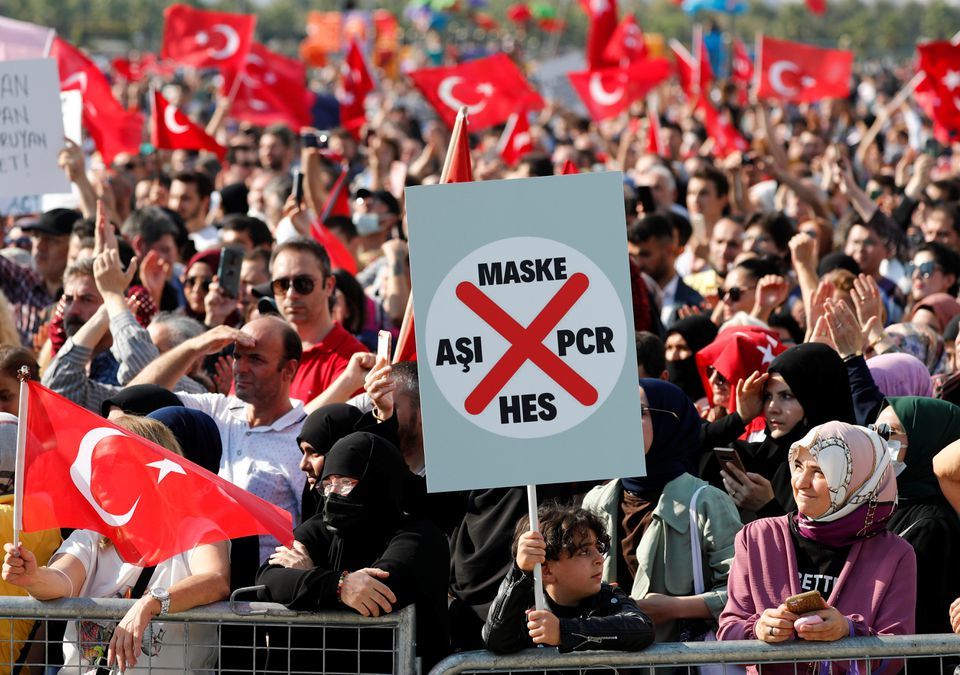 A boy holds a placard as anti-vaccine demonstrators wave Turkish flags during a protest against official coronavirus-related mandates, including vaccinations, tests and masks, in Istanbul, Turkey on September 11. &mdash; Reuters