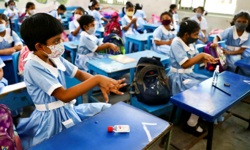 Students apply hand sanitiser while attending a class at the Viqarunnisa Noon School & College after the government withdrew restrictions on educational institutions following a decrease in the number of cases of coronavirus in Dhaka, Bangladesh, on Sunday. — Reuters