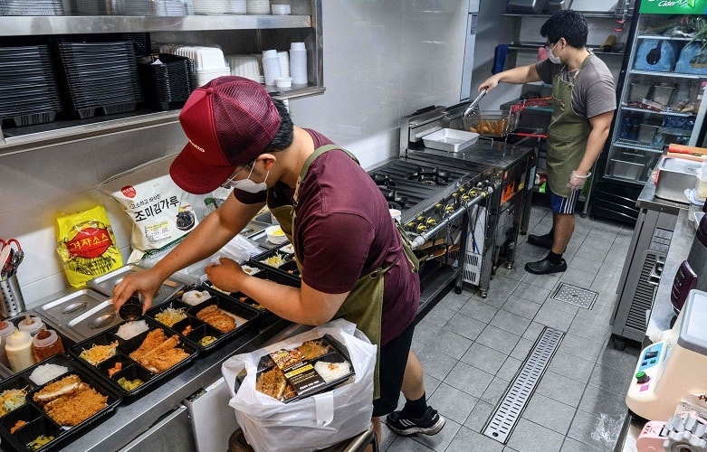 This picture taken on Sept 1, 2021 shows 'Donkatsu Kitchen' workers preparing meat cutlet lunch boxes in their rented 'ghost kitchen' in Seoul. — AFP
