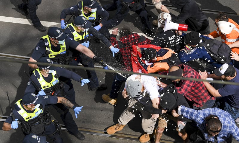 Victoria police fire pepper spray during a clash with protesters at a rally in Melbourne, Australia. — AP