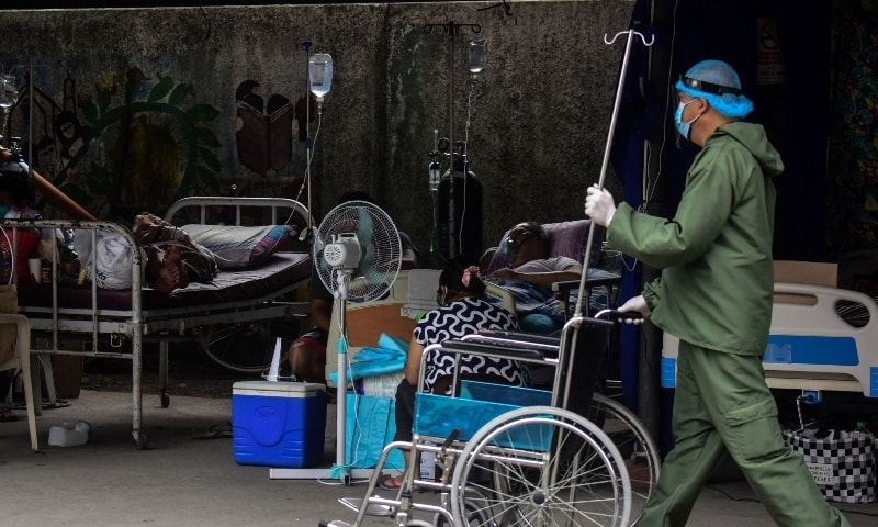 This file photo taken on September 6 shows a nurse in a personal protective suit walking past patients suspected of having Covid-19 in a parking lot-turned-into ward outside a hospital in Binan, Laguna province. — AFP
