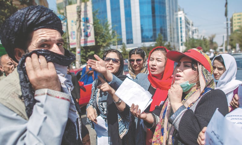 Women converse with a man during the demonstration in front of the former ministry of women affairs.—AFP