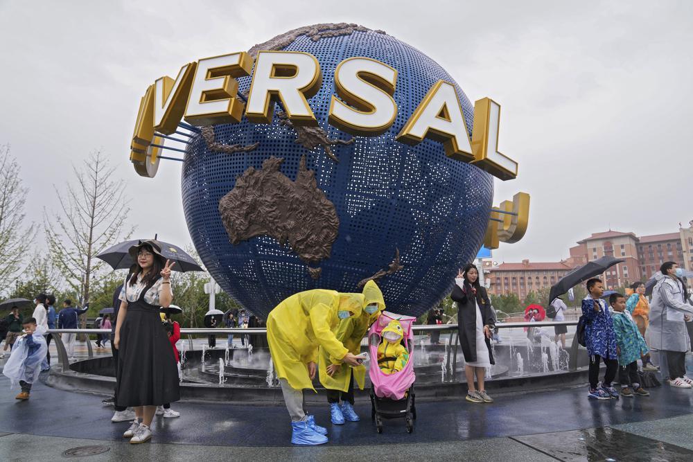 A family wearing raincoats and face masks to help protect themselves from the coronavirus pose for a selfie with an icon near the entrance to the Universal Studios Beijing in Beijing, China, on September 20. — AP