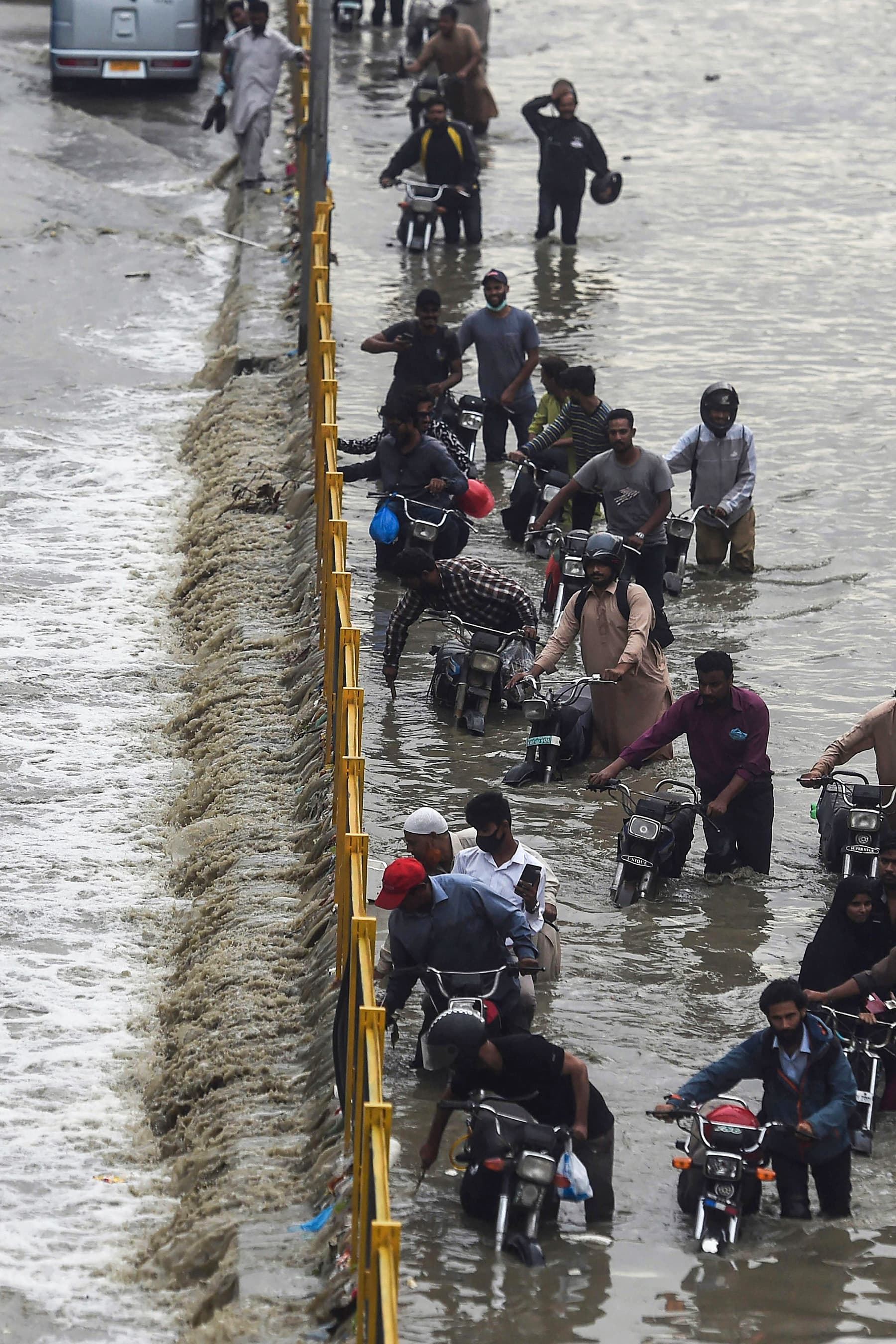 Commuters cross a flooded street after heavy rainfall in Karachi on September 23. — AFP