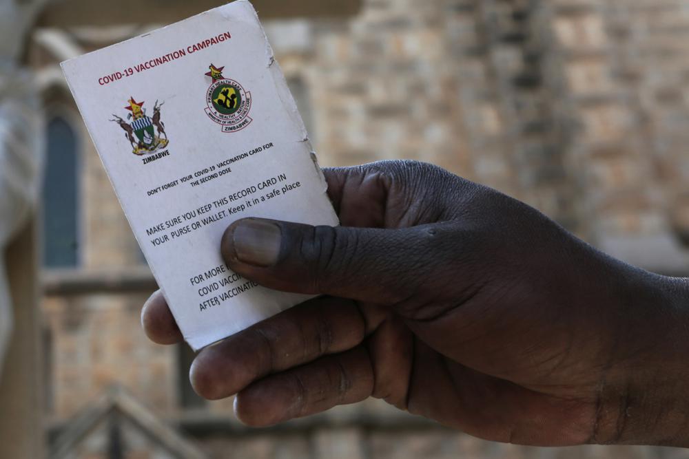 A government worker shows his vaccination card in Harare, Zimbabwe on Sept 19. — AP