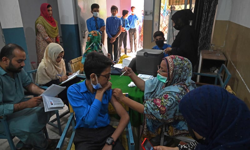 A health worker inoculates a student with a dose of Pfizer vaccine against Covid-19 at a school in Lahore. — AFP