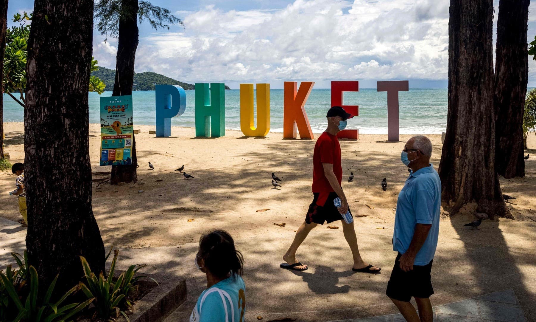 In this file photo taken on August 14, 2021, people wearing face masks visit Patong Beach in Phuket as tourists take advantage of the &ldquo;Phuket Sandbox&rdquo; programme for visitors fully vaccinated against the coronavirus. &mdash; AFP
