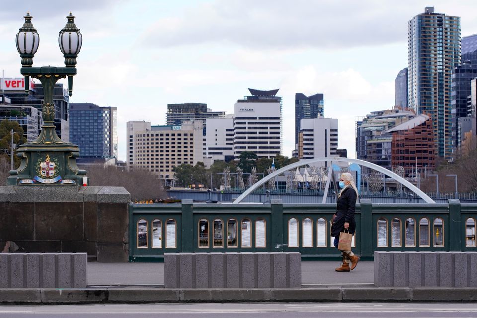A lone woman, wearing a protective face mask, walks across a city centre bridge as the state of Victoria looks to curb the spread of a coronavirus outbreak in Melbourne, Australia, July 16. &mdash; Reuters