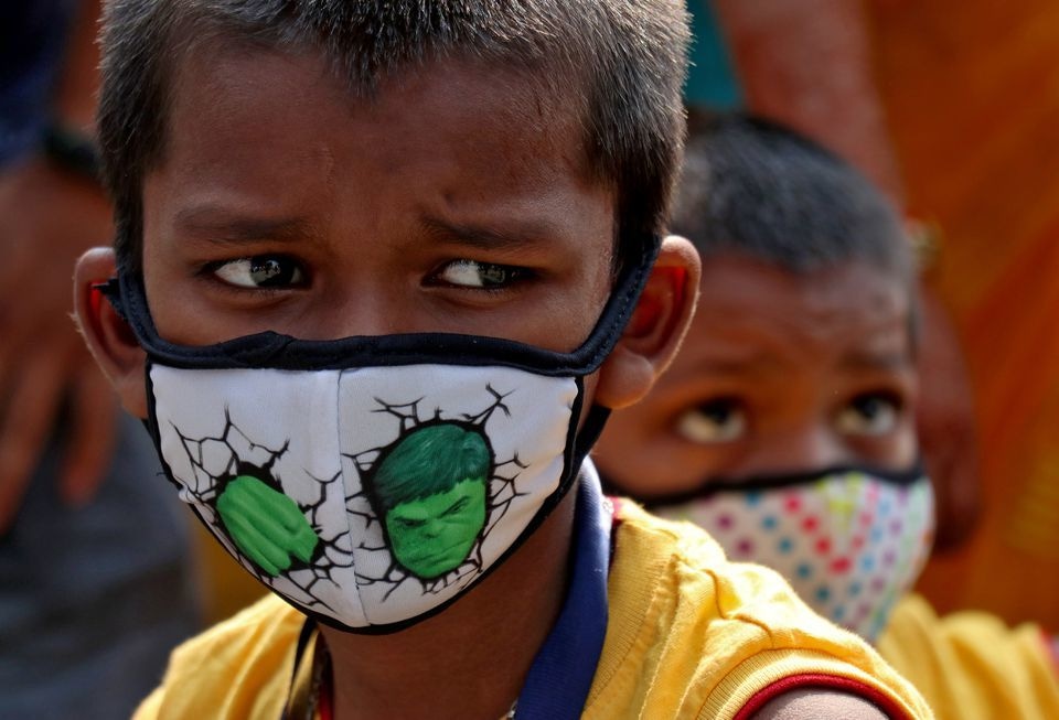 Children wearing protective masks wait to enter the Lokmanya Tilak Terminus railway station in Mumbai on April 14. — Reuters