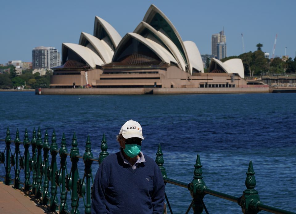 A person in a protective face mask walks along the harbour waterfront across from the Sydney Opera House during a lockdown in Sydney, Australia, October 6. &mdash; Reuters