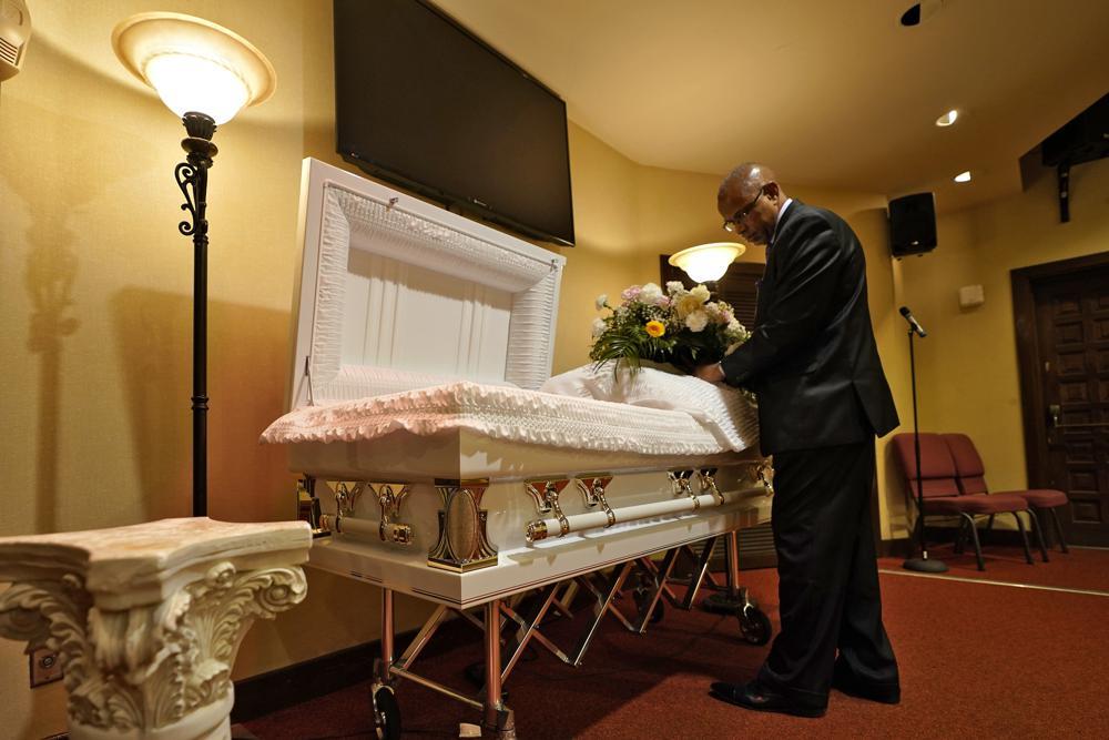 A funeral director arranges flowers on a casket before a service in Tampa, Florida, US, Sept 2. &mdash; AP