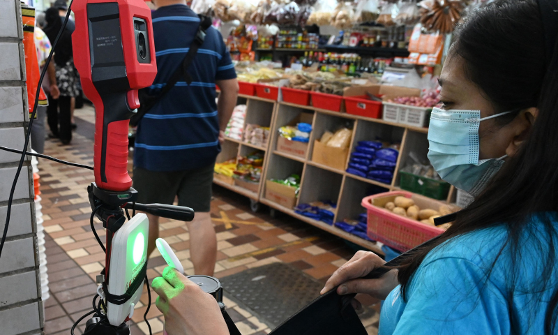 A resident scans the TraceTogether token, used to aid contact tracing efforts relating to the ongoing Covid-19 situation, to enter a market in Singapore on Saturday. — AFP