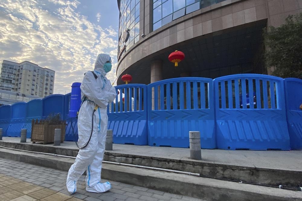 In this file photo, a worker in protective overalls and carrying disinfecting equipment walks outside the Wuhan Central Hospital. — AP