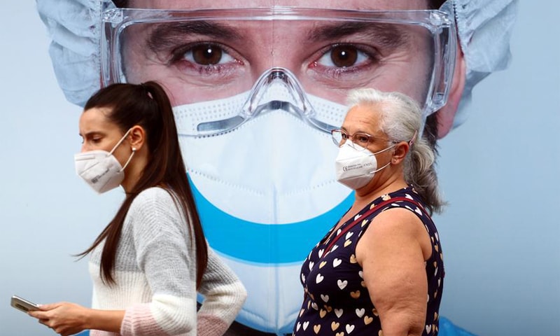 In this file photo, people wearing protective face masks walk past a dental clinic advertisement in Vallecas neighbourhood in Madrid, Spain. — Reuters/File