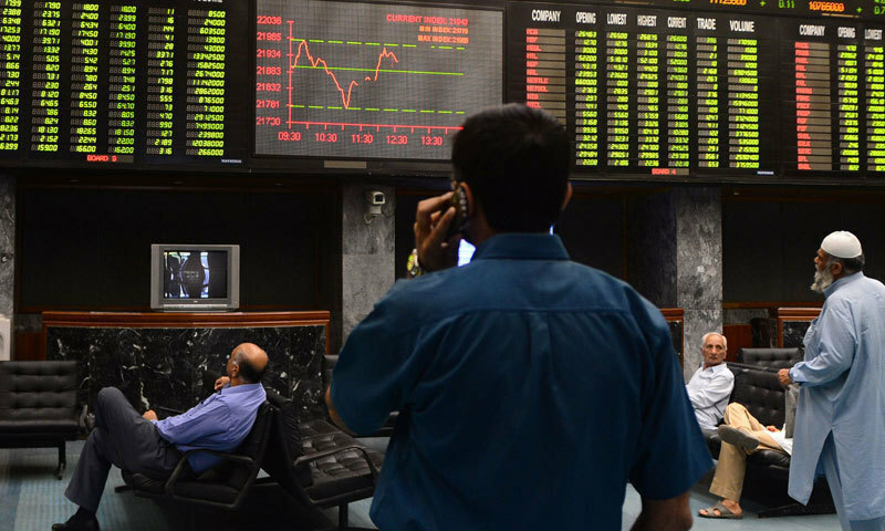 A man speaks on his cellphone in this file photo as he watches share prices on a screen at the Pakistan Stock Exchange (PSX) in Karachi. — AFP/File