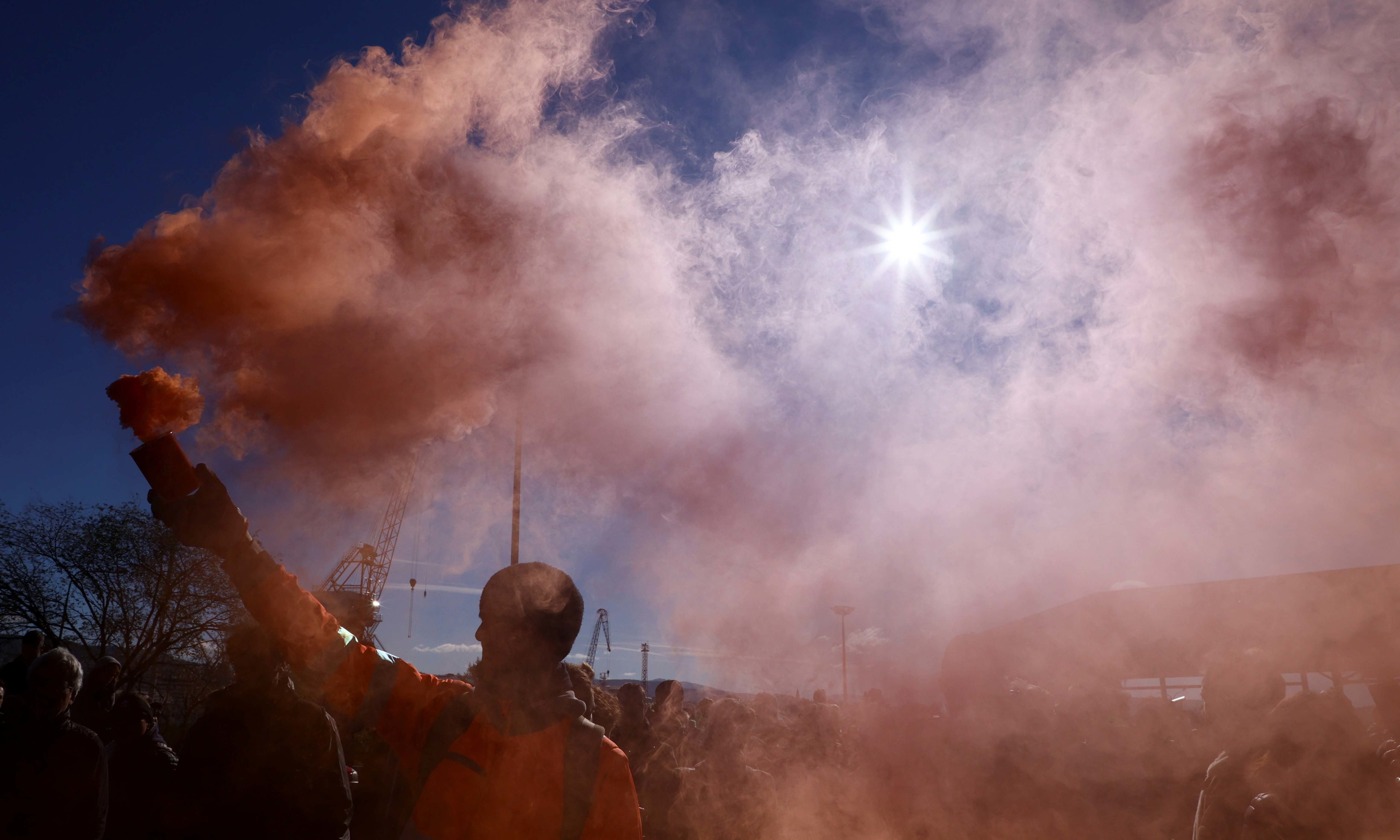 A person holds a flare as port workers gather outside the entrance of the major port of Trieste to protest against the implementation of the Covid-19 health pass in the workplace, on October 15. &mdash; Reuters