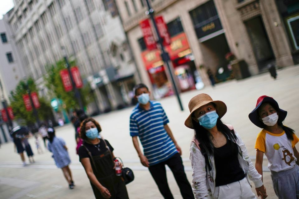 People wearing protective face masks walk on a street, following new cases of the coronavirus in Shanghai on August 25. &mdash; Reuters