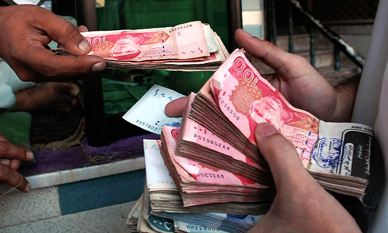 A man holds a bunch of Pakistani currency notes in this file photo. — AP