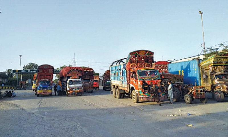 GUJRAT: Trucks and trailers parked near the Chenab bridge which has been blocked  by the authorities by digging a trench and  placing containers to prevent a banned outfit followers from marching on Islamabad. &mdash; Dawn