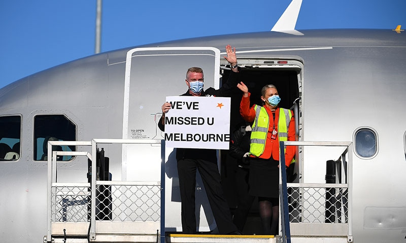 Flight crew wave to the media holding a sign in the doorwell of Jetstar flight JQ505 which arrived from Sydney at Tullamarine Airport in Melbourne, Australia, on Monday. — Reuters