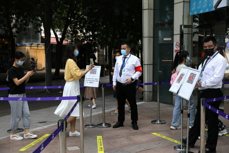 A woman shows her health status on a phone to a security guard, at an entrance of a shopping mall in Beijing, China, August 23. — Reuters
