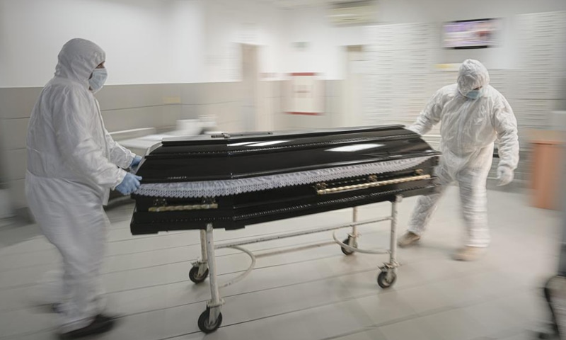 Funeral house employees drag a coffin on a trolley as they arrive at the University Emergency Hospital morgue to take a Covid-19 victim for burial in Bucharest, Romania. — AP