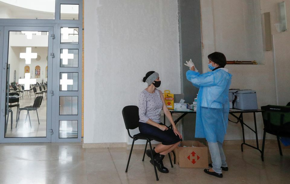 A medical worker fills a syringe as a woman waits before receiving a dose of a vaccine against the coronavirus at a vaccination centre located in the Cathedral of the Resurrection of Christ in Kyiv, Ukraine, November 8. &mdash; Reuters