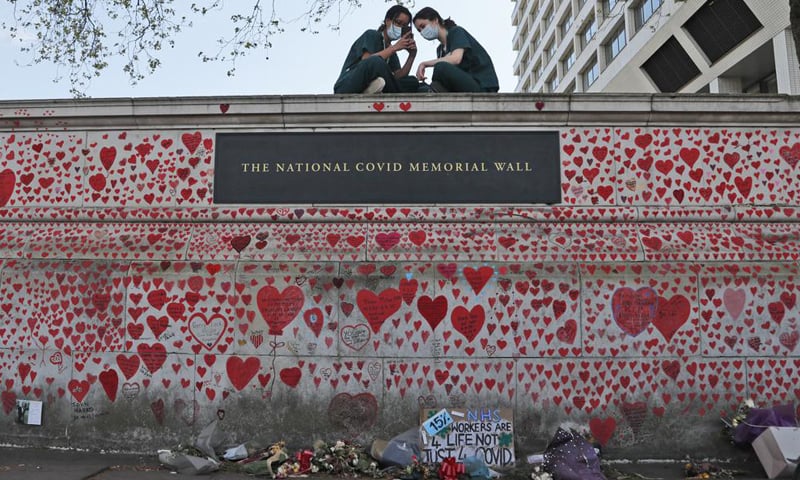 In this file photo, nurses from the St Thomas' hospital sit atop the National Covid Memorial Wall in London. — AP/File