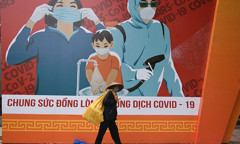 Awoman walks past a billboard with information on preventing the spread of the Covid-19 coronavirus in Hanoi. — AFP/File