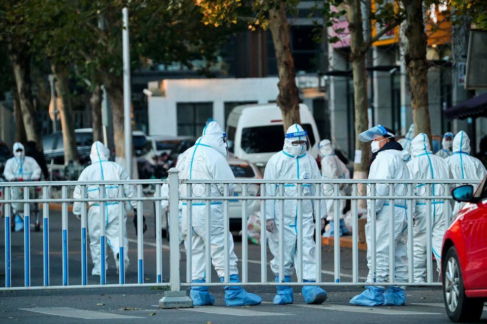 Security personnel in protective suits guard the perimeter of a residential compound locked down after a local outbreak of the coronavirus in Beijing, China, November 11. — Reuters