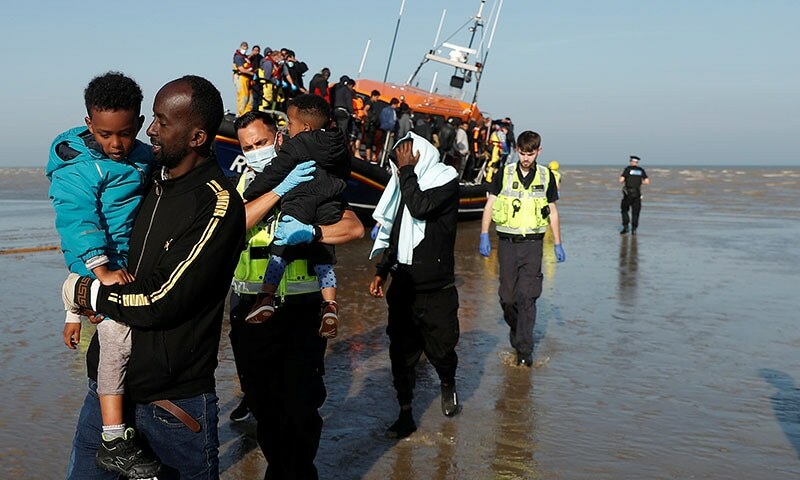 A migrant rescued from the English Channel carries a child after arriving on a Royal National Lifeboat Institution (RNLI) boat at Dungeness, Britain. — Reuters/File