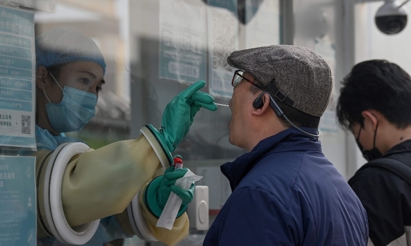 A health worker takes a swab sample from a man to test for the coronavirus at a nucleic acid collection station in Beijing, China, Oct 25. &mdash; AFP