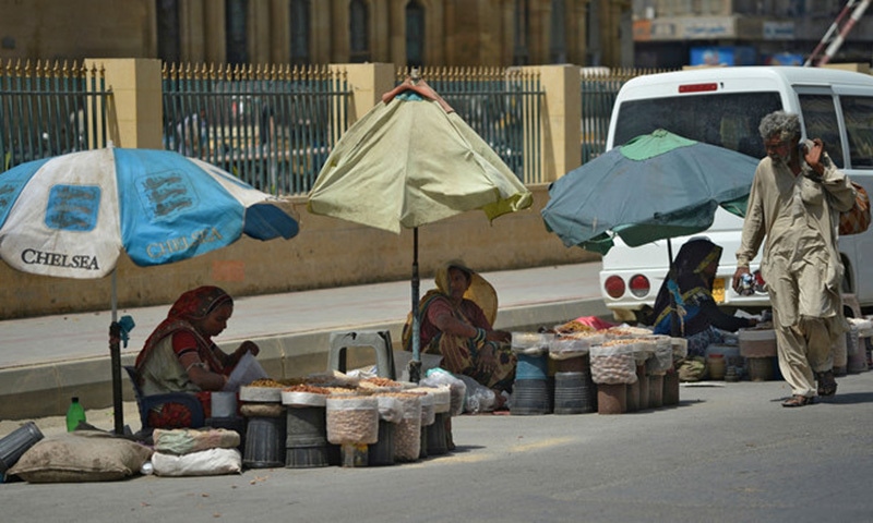 Women vendors wait for customers alongside a street in Karachi. — AFP/File