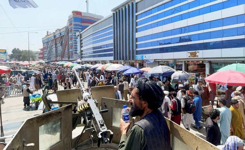 Members of Taliban security forces stand guard as crowds of people walk past in front of a money exchange market in Kabul, Afghanistan on Sep 4, 2021. — Reuters