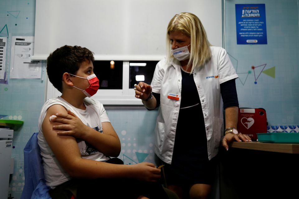 Noam Kleinmann, 10, chats with the nurse while he receives his first coronavirus vaccination after Israel approves vaccinations for children aged 5-11, in Tel Aviv, Israel, November 22. &mdash; Reuters