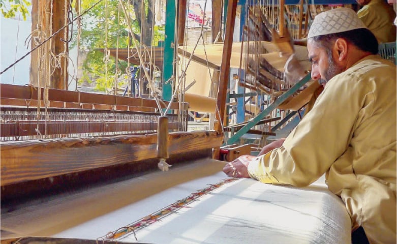 A worker weaves woolen shawl on his handloom in Salampur village, Swat. &mdash; Dawn